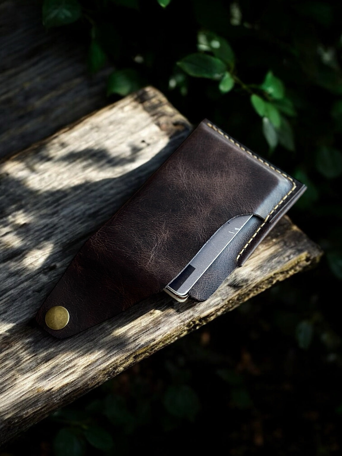 Kahverengi deri el yapımı kartlık – kapak açık şekilde, kart çıkarken ahşap yüzeyde