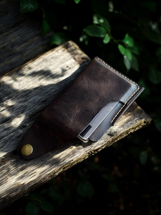 Kahverengi deri el yapımı kartlık – kapak açık şekilde, kart çıkarken ahşap yüzeyde