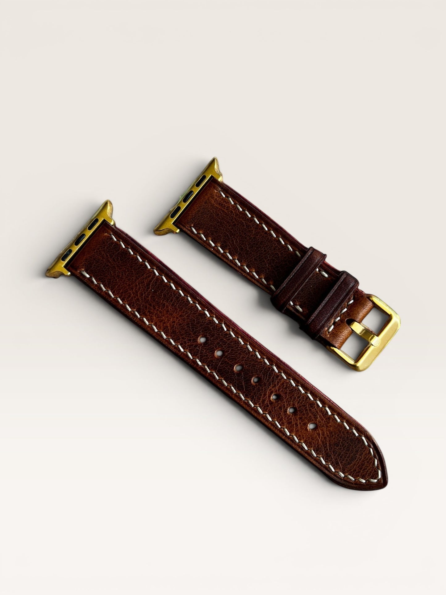 Safir Leather çift kat kahverengi deri Apple Watch saat kayışı, beyaz dikişli, altın rengi toka ve adaptörlü.