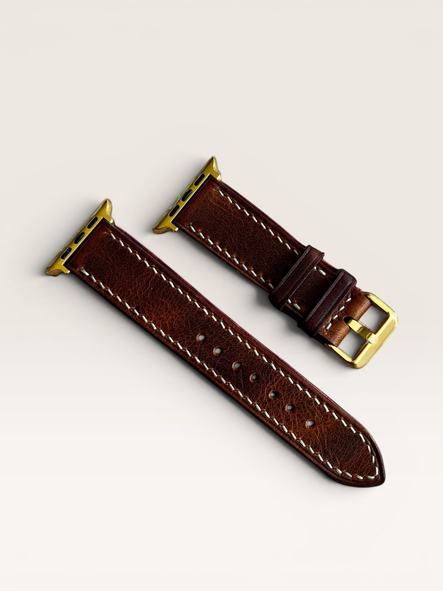 Safir Leather çift kat kahverengi deri Apple Watch saat kayışı, beyaz dikişli, altın rengi toka ve adaptörlü.