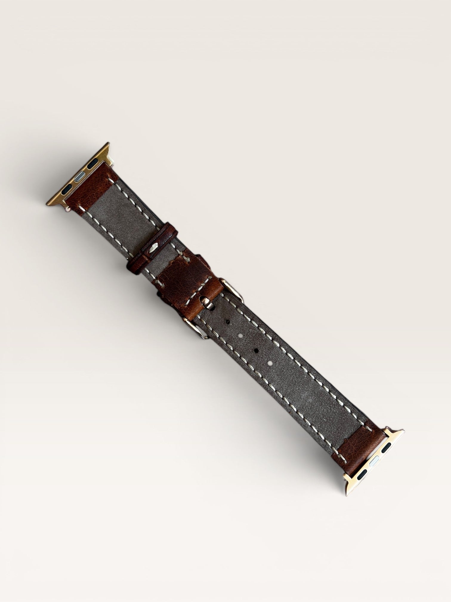 Safir Leather çift kat deri Apple Watch kordonu, kahverengi ve gri renklerde, paslanmaz çelik tokalı ve adaptörlü.