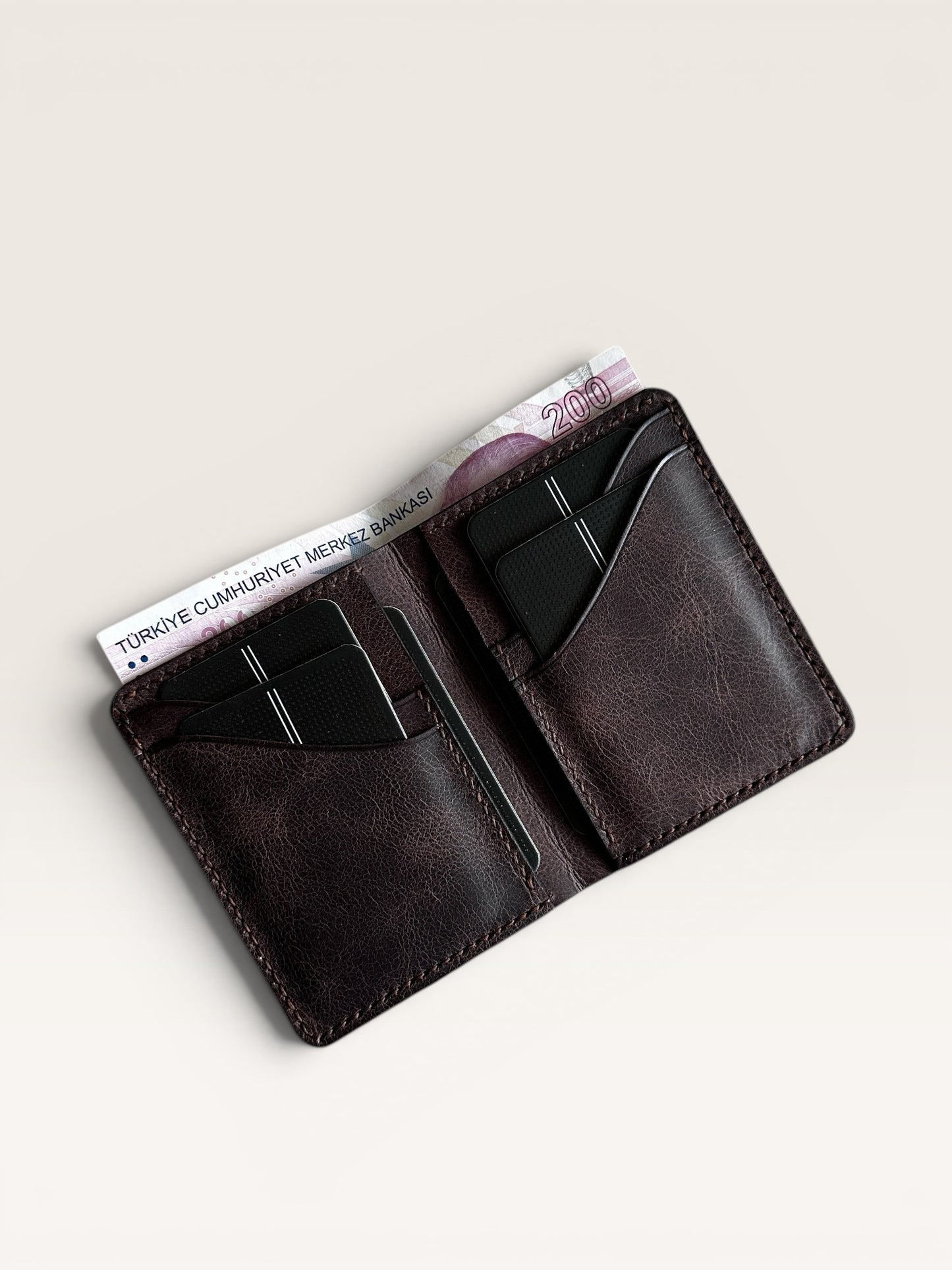 Safir Leather hakiki deri, derin kahve rengi, minimalist el yapımı cüzdan. 10.5x8.5 cm boyutlarında, 6-12 kart kapasiteli.