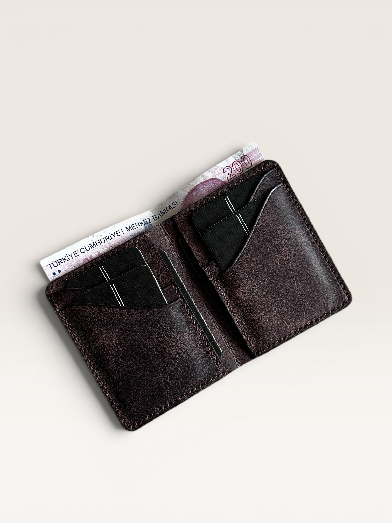 Safir Leather hakiki deri, derin kahve rengi, minimalist el yapımı cüzdan. 10.5x8.5 cm boyutlarında, 6-12 kart kapasiteli.