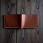 Safir Leather kızıl vajetal deri cüzdan, el yapımı mumlu dikişli minimal tasarım, koyu ahşap zemin üzerinde