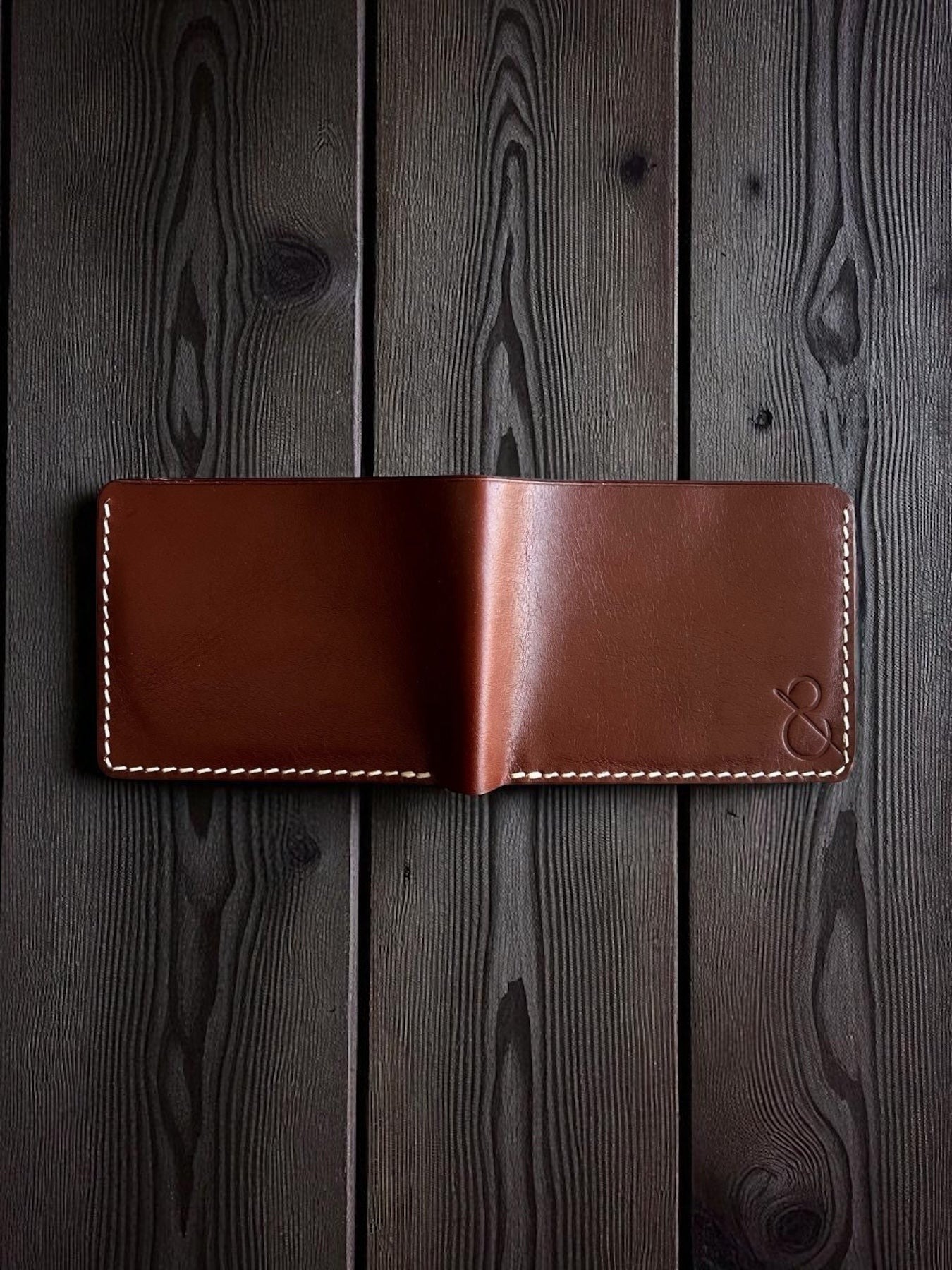 Safir Leather kızıl vajetal deri cüzdan, el yapımı mumlu dikişli minimal tasarım, koyu ahşap zemin üzerinde