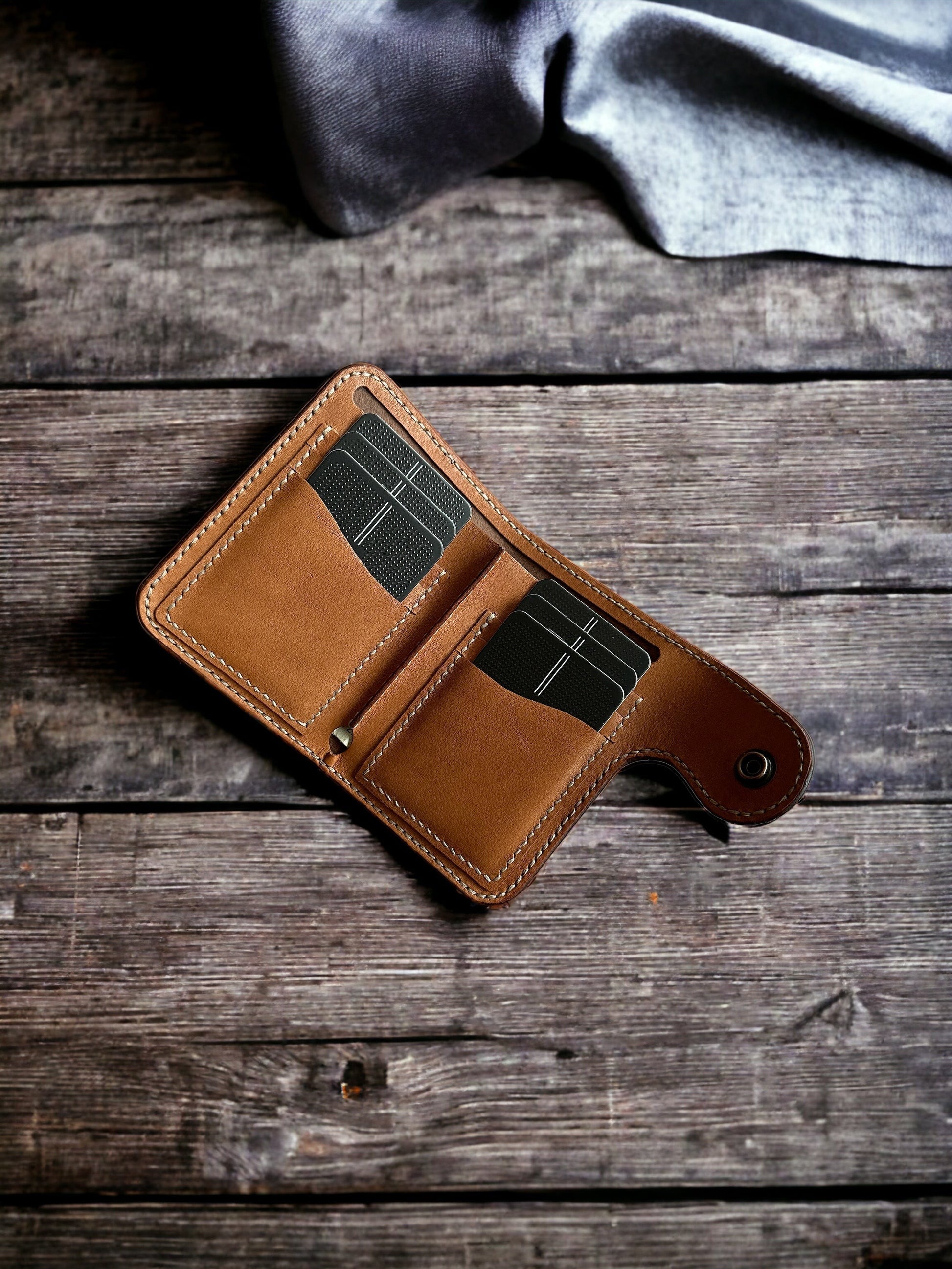 Safir Leather taba rengi el yapımı hakiki deri cüzdan, minimal tasarım ve kart bölmeleri ile ahşap zemin üzerinde.